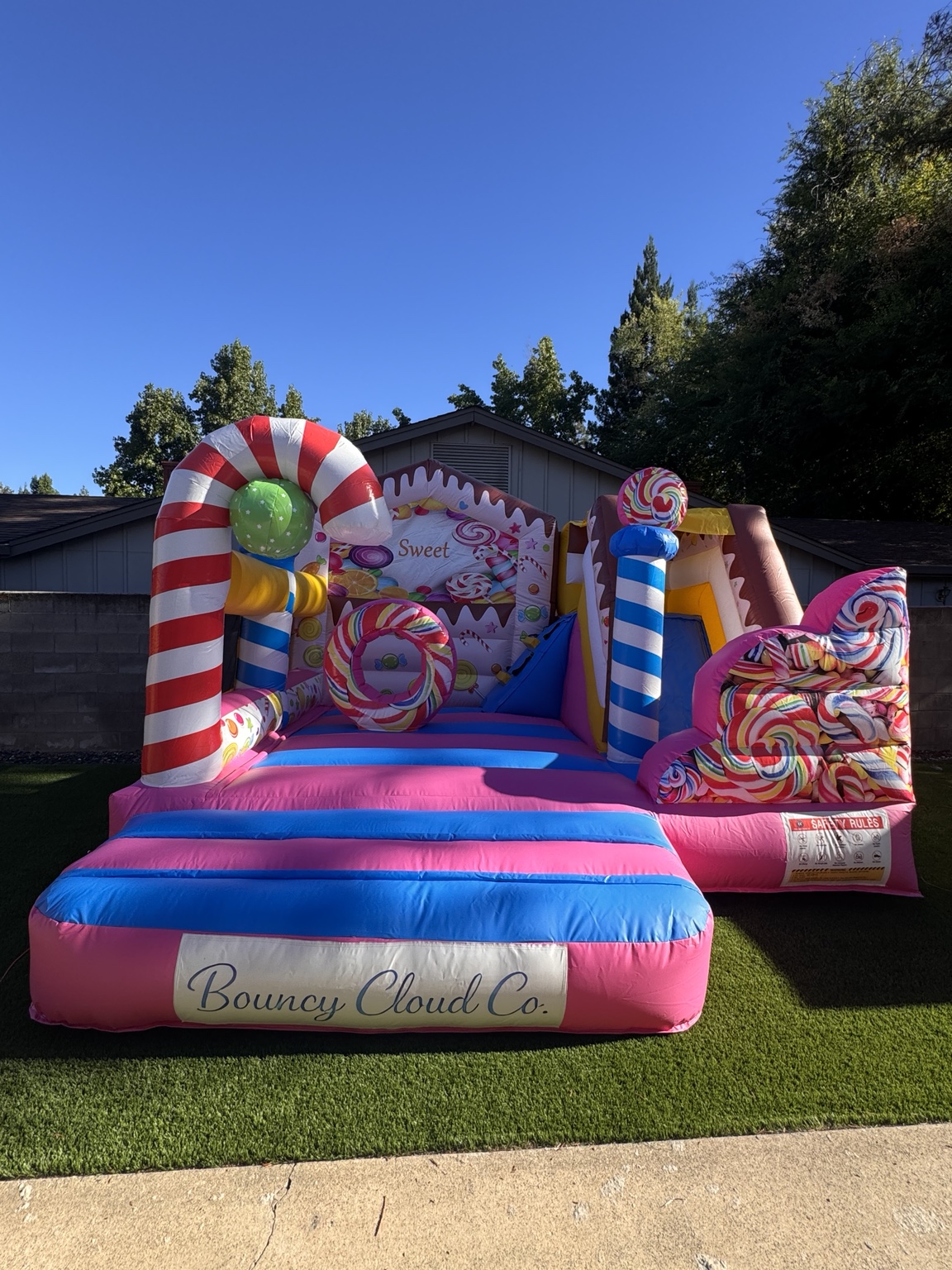 Candy Cloud’s pink and blue bounce house with candy-cane arch, lollipops, and slide